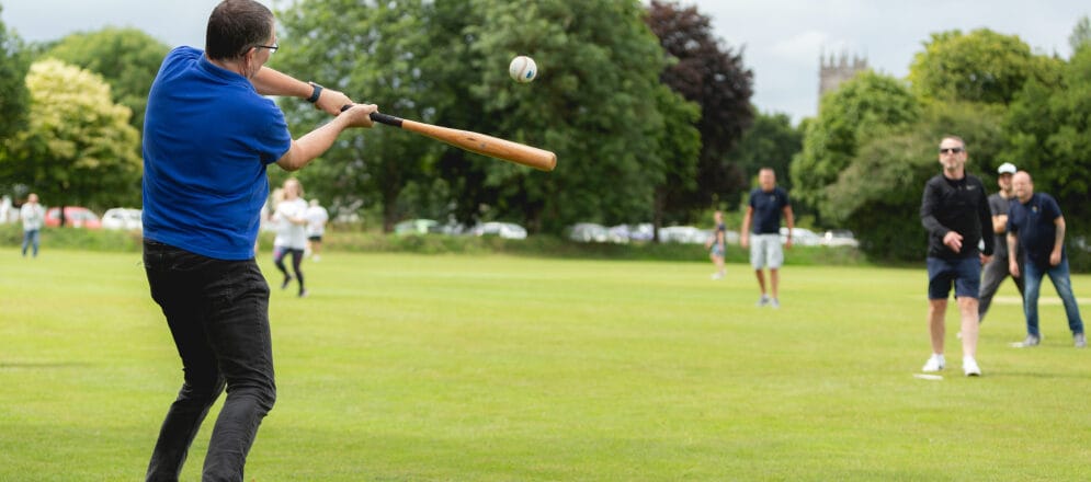 Man swinging a bat while playing rounders at the annual Goonvean Games